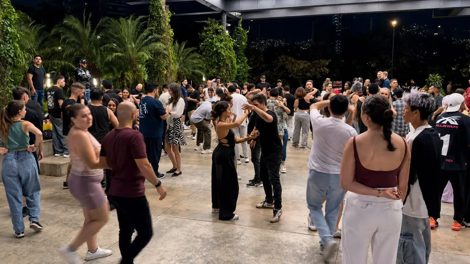 A large group dancing bachata together outdoors in Medellín at night